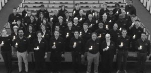 A group of people dressed in black hold candles