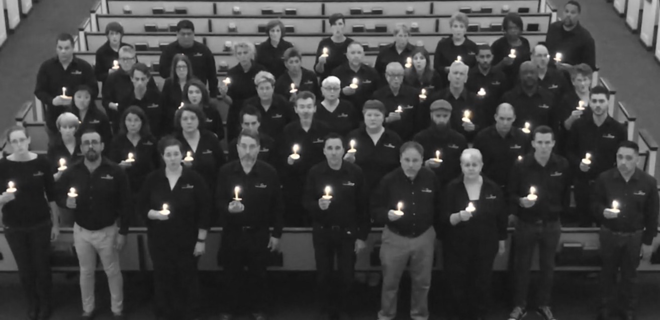 A group of people dressed in black hold candles