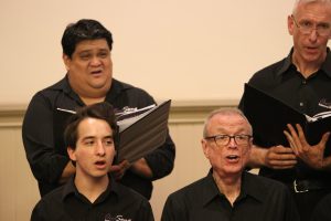 Choir members perform, some read from binders