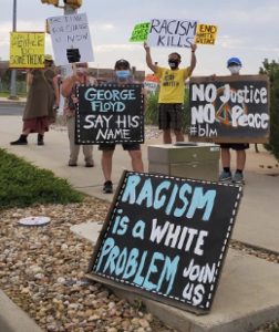 A group of protestors hold signs protesting racism