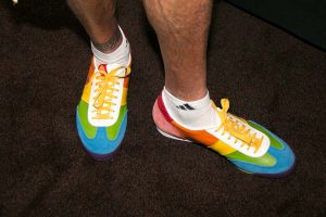 a person'e hairy legs with white socks and rainbow colored sneakers