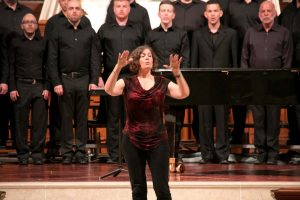 Jane Ramseyer Miller conducting in front of a group of singers