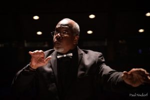 Photo of Steve Milloy conducting. 