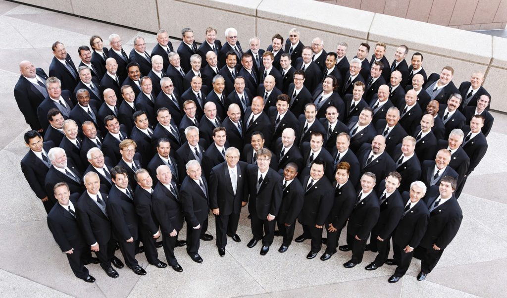 about 100 men in black suits and white shirts as seen from above