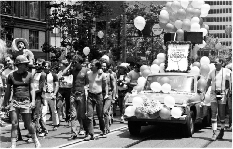 A black and white photo of the San Fransisco Gay Mens Choir at a parade.