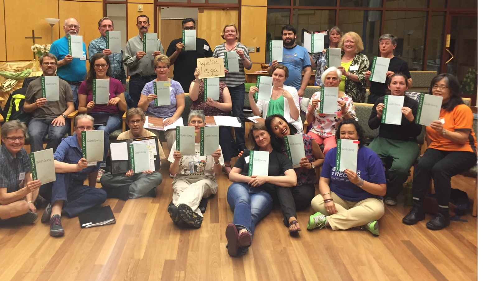 Mixed chorus holding copies of published sheet music.