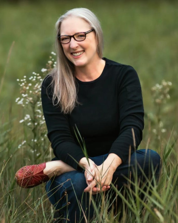 Elizabeth Alexander sits in a field of grass, smiling.