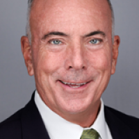 headshot of a smiling man in a suit with a green tie - short hair