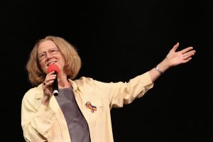 Holly Near sings into a microphone at Festival 2016 in Denver.