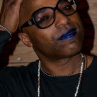 headshot of Abby Hall, black person with bald head and blue lipstick