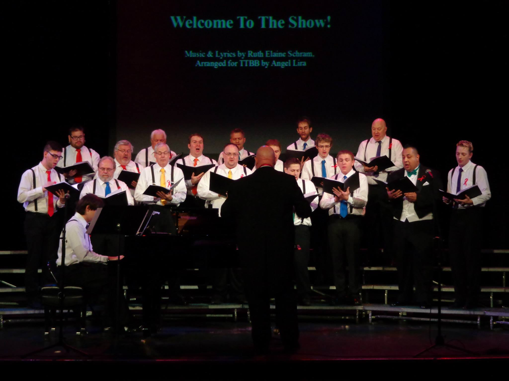 A choir performs with a conductor in the foreground