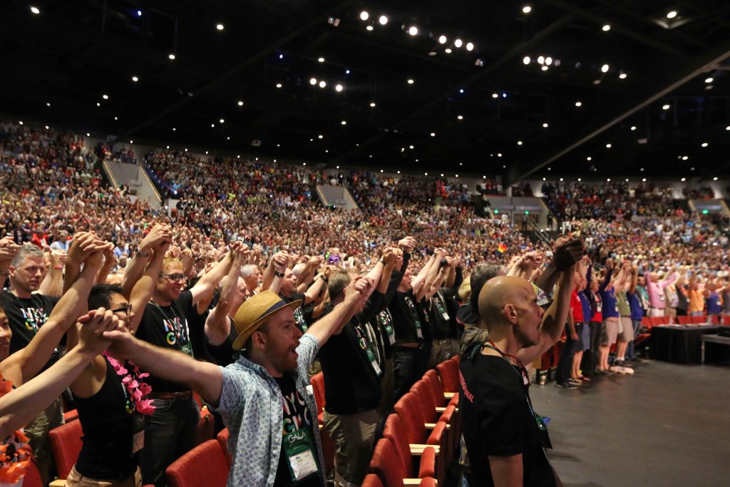 An audience sings along and holds their hands up