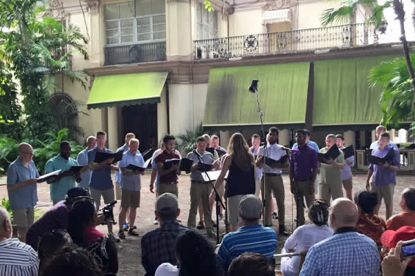 A choir sings outdoors for an audience