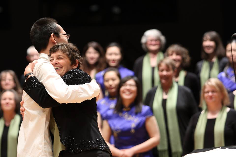 Two people embrace before a chorus of onlookers