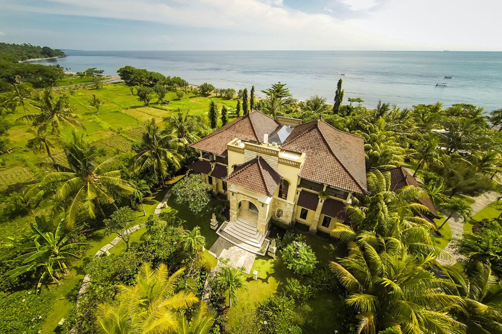 A beautiful villa in Bali next to the ocean, surrounded by green palm trees