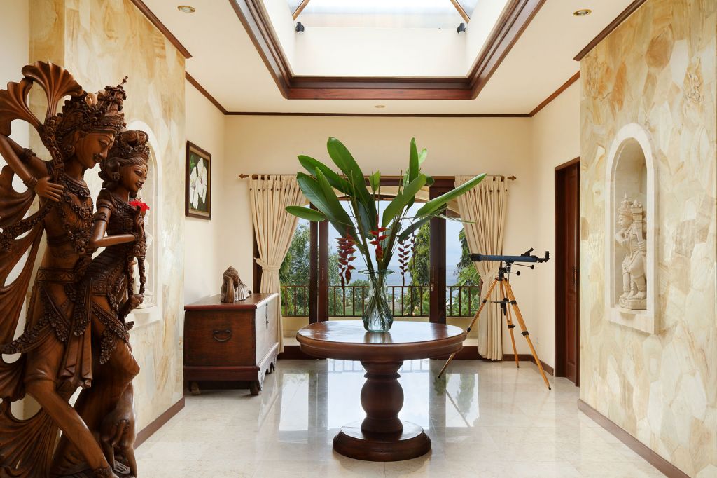 the opulent foyer of a villa in bali with marble floors and wooden sculptures