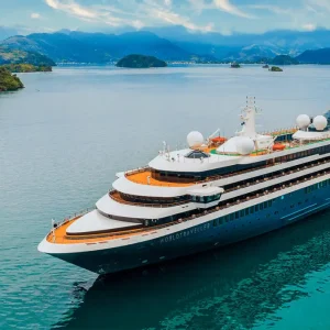 A cruise ship sits on placid turquoise waters off the coast of Ireland.