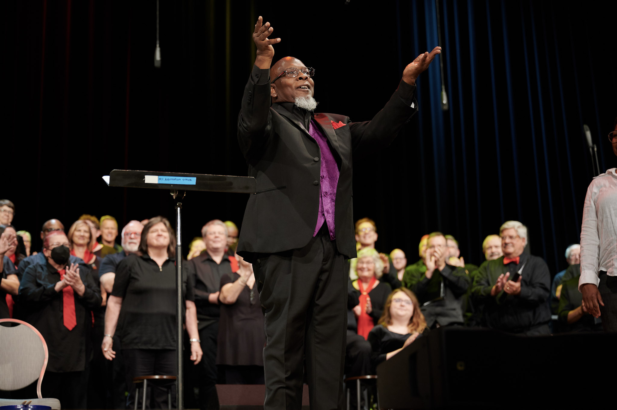 Steve Milloy raises his arms in front of a choir at Festival 2024.