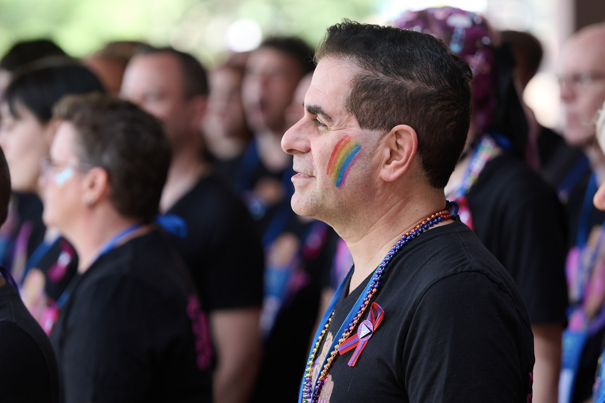 A delegate with short dark hair and a rainbow on their cheek stands outside at Festival 2024.