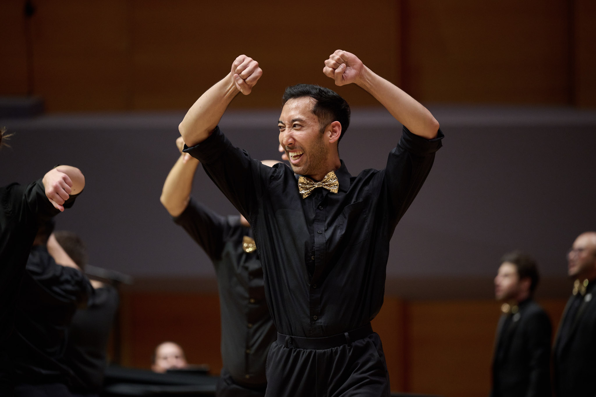 A singer wearing a black shirt and pants with a golden bow tie dances on stage at Festival 2024.