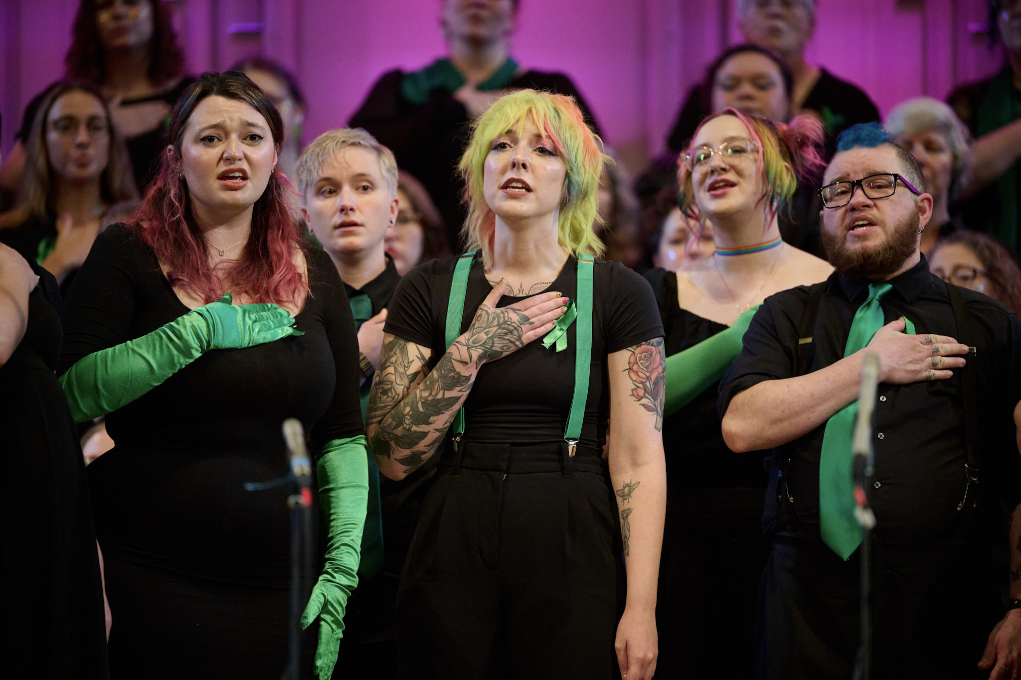 The Denver Women's Chorus performs at Festival 2024 wearing black with green accent pieces.