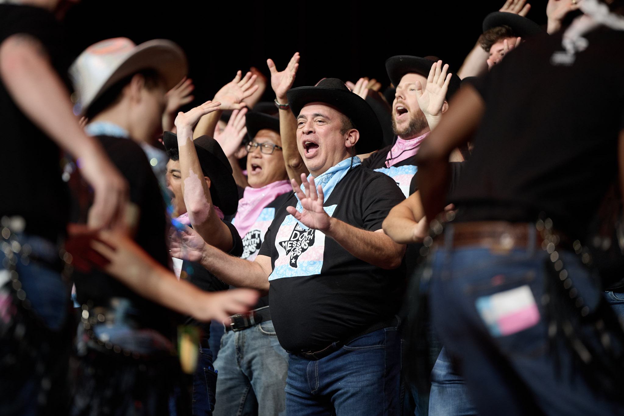 A singer wearing a black cowboy hat performs with similarly a dressed group at Festival 2024.