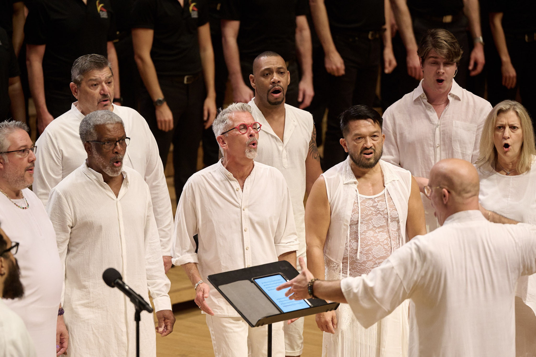 A choir performs at Festival 2024 wearing all white, conducted by Anthony Cabrera.