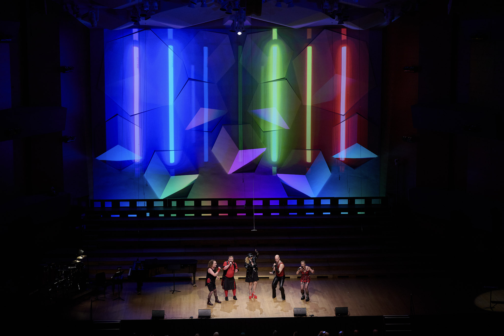 A small ensemble performs on the Orchestra Hall stage with rainbow lights projected on the wall behind at Festival 2024.