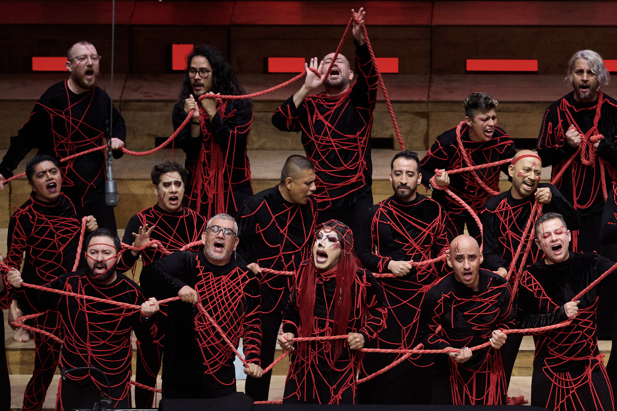 Coro Ciudad de Mexico performs at Festival 2024, wearing black with red rope and yarn covering and connecting them.