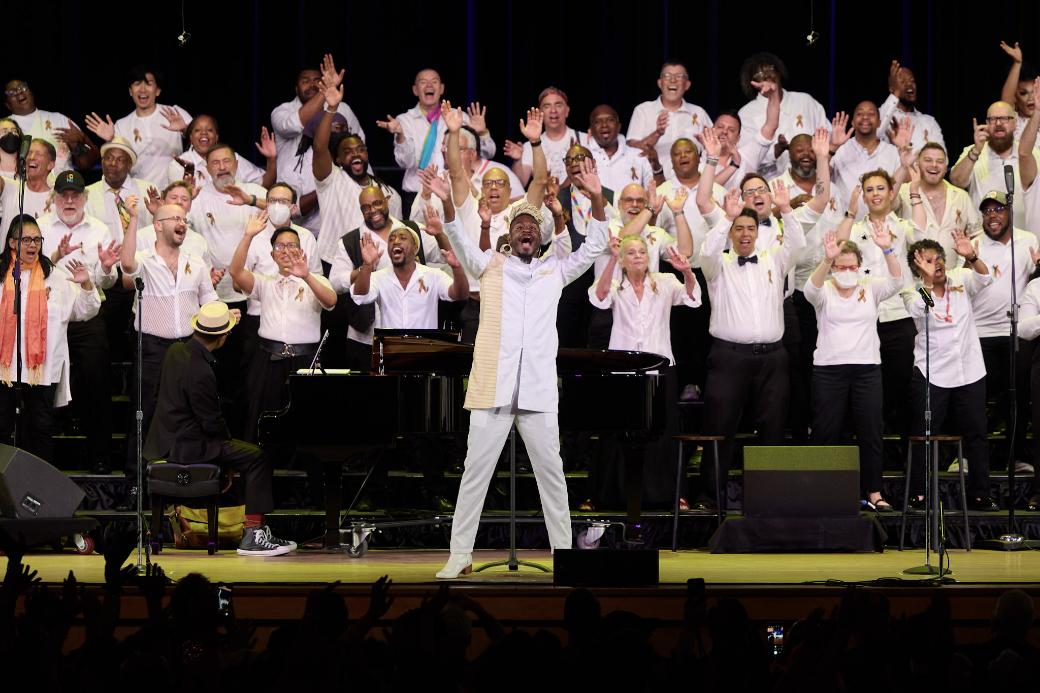 The Queer Gospel Choir performs with their hands raised up in the air, conducted by Eric Williamson, at Festival 2024.