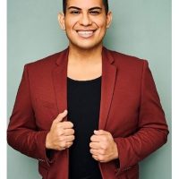 Gabe Salazar smiles wearing a maroon suit and a black shirt.