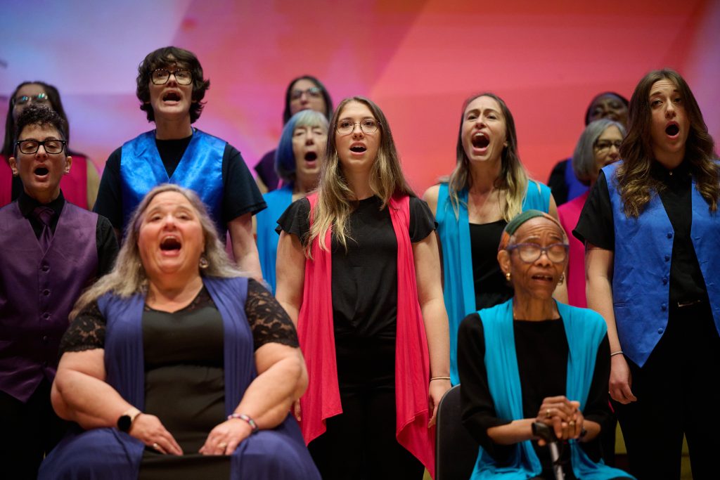 ANNA Crusis Feminist Choir performs at Festival 2024 in front of a pink and purple backdrop.