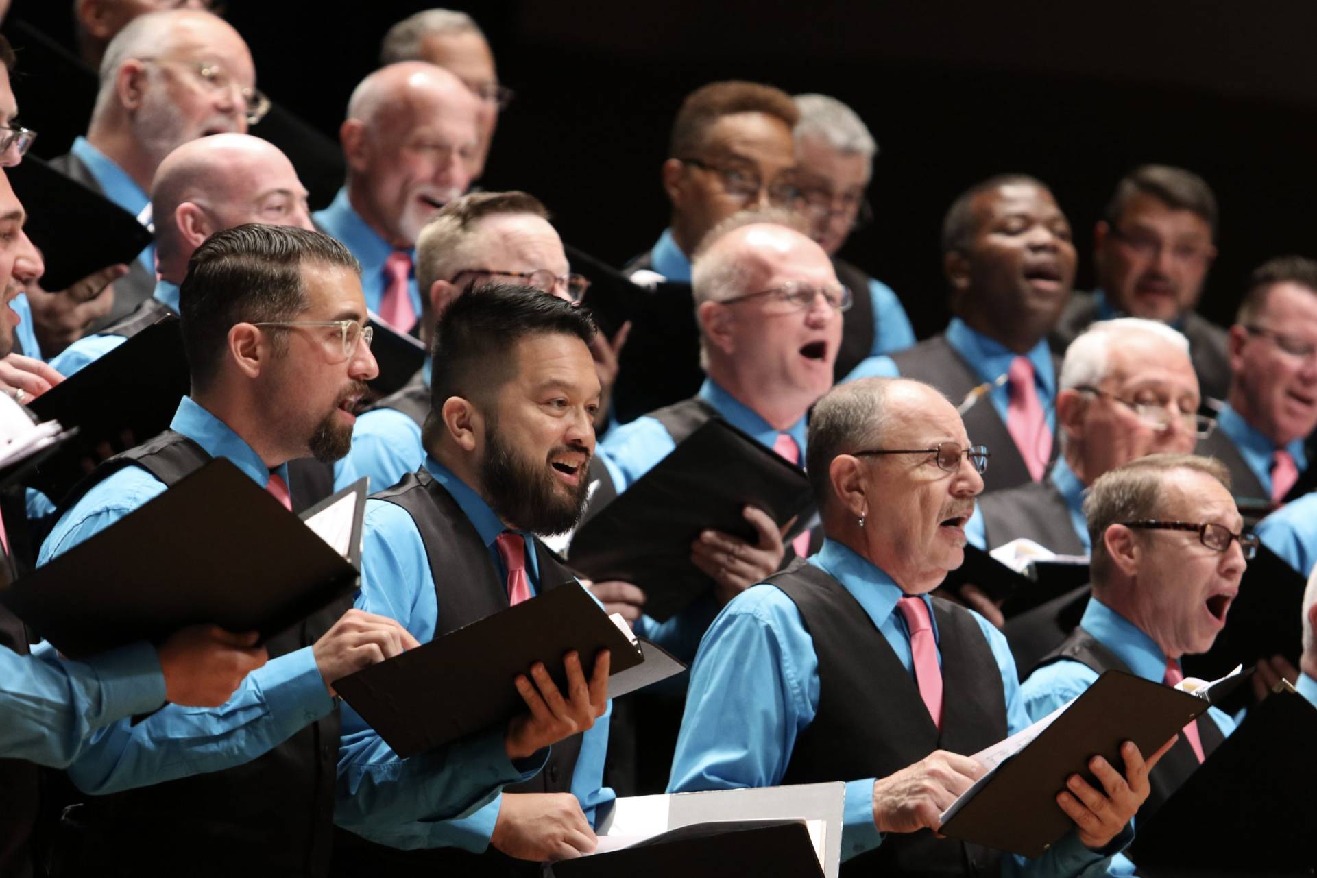 men in suits holding binders and singing